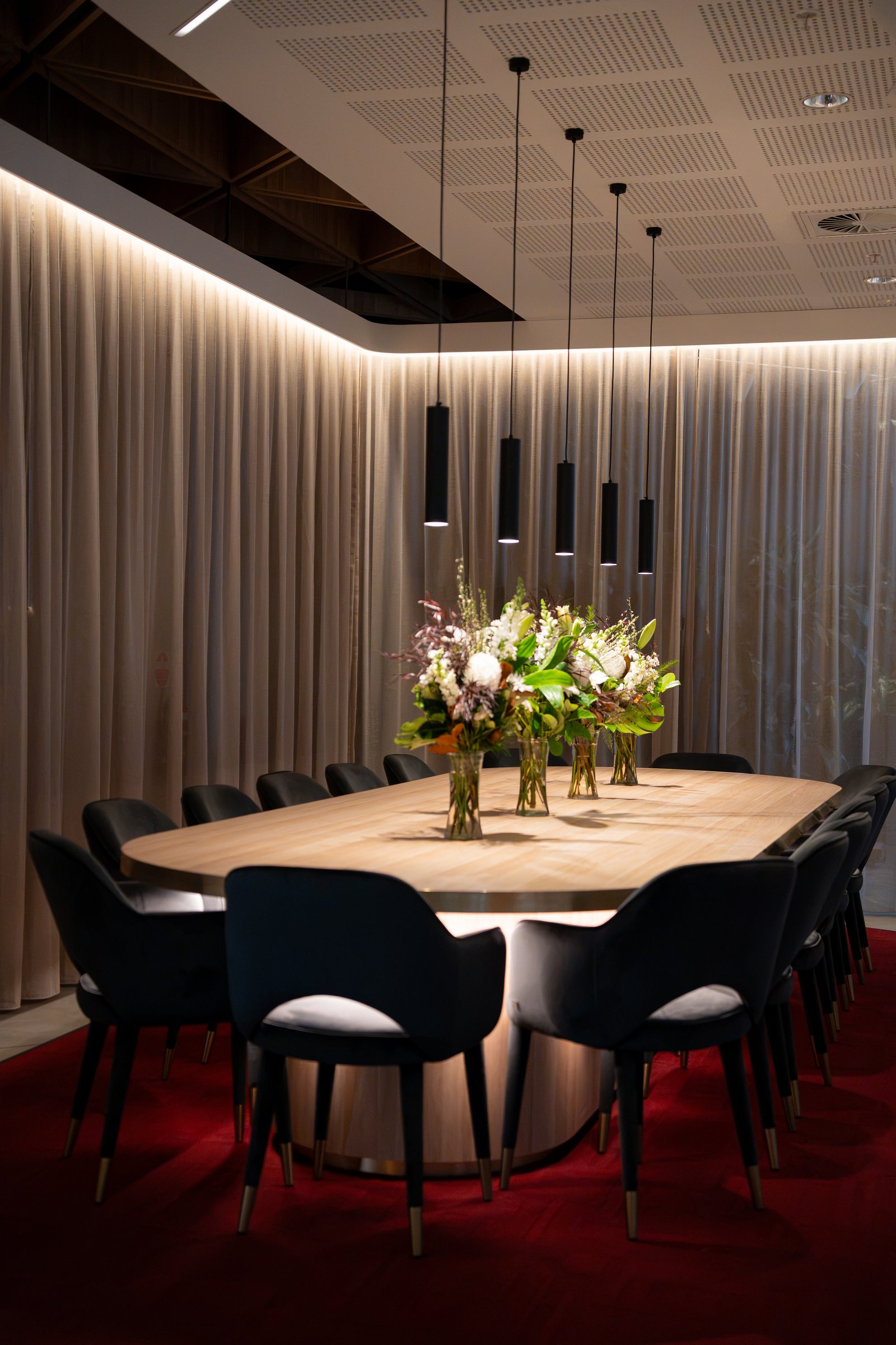 Long private dining table with flowers under pendant lights